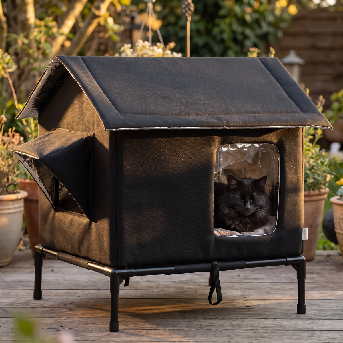 Haven Raised Weatherproof Pet House with a black cat in the evening